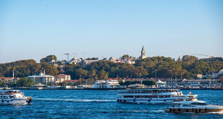 Boote auf einem Gewässer mit Stadtpanorama im Hintergrund.