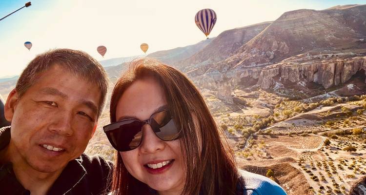 Paar mit Heißluftballons im Hintergrund.