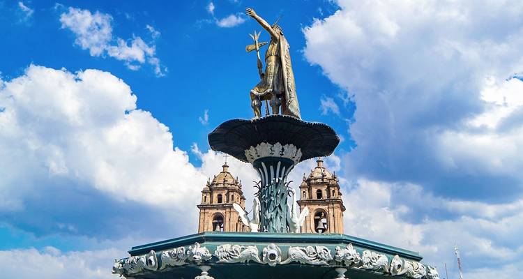Standbeeld boven een fontein met een historische kerk op de achtergrond.
