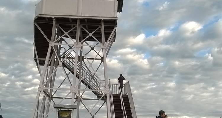 Metallener Wachturm vor bewölktem Himmel.