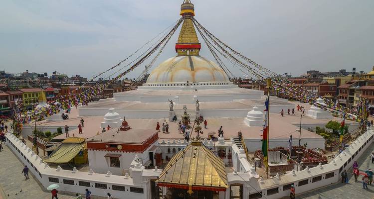 Große Stupa mit Gebetsfahnen in städtischer Umgebung.