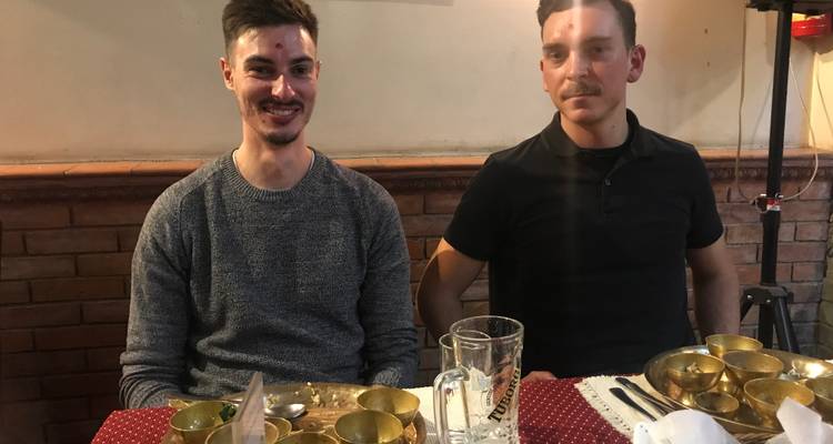 Zwei Männer sitzen an einem Esstisch mit angerichteten Mahlzeiten.