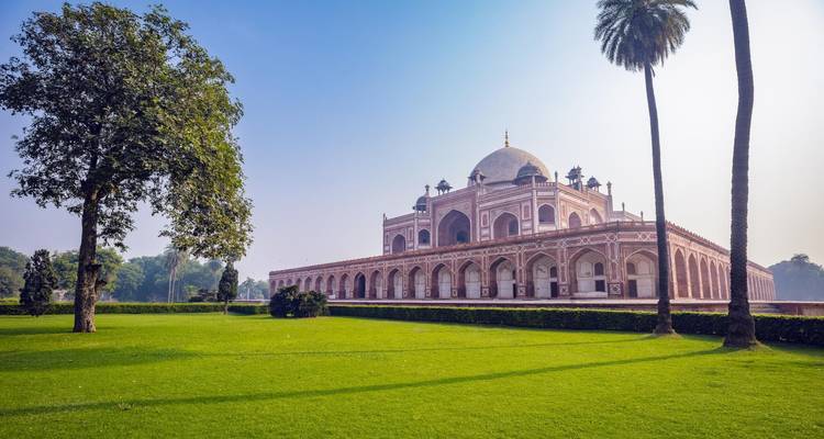 Historic domed building with lush green lawns and trees.