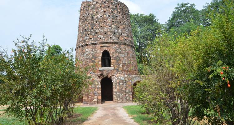 Old stone tower surrounded by green foliage and trees.