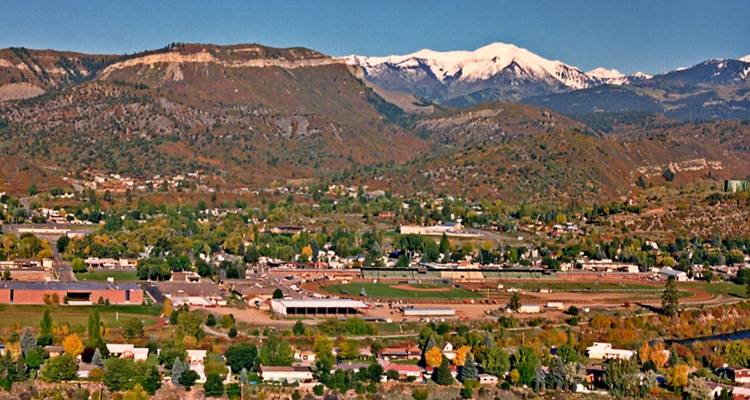 Panoramic view over Durango valley dotted with fall colors and backed by snow-capped peaks under a clear sky