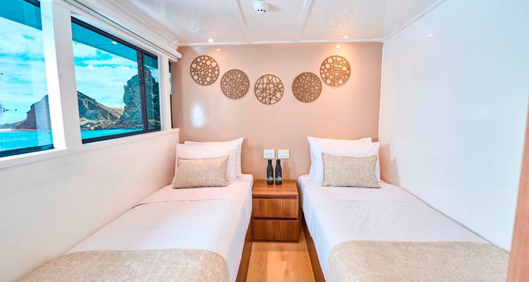 Cabine de bateau avec deux lits simples et décoration, vue sur l'océan