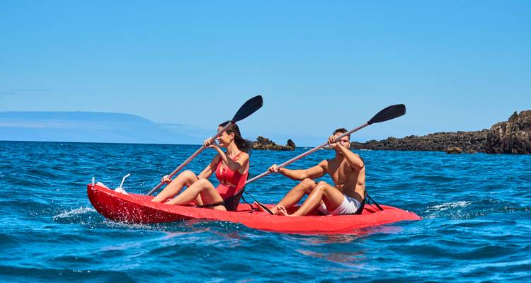 Couple faisant du kayak sur un océan bleu clair.