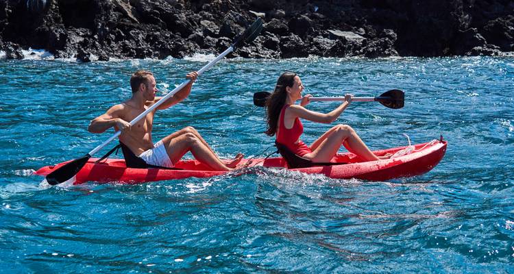 Deux personnes faisant du kayak sur une eau bleue claire.