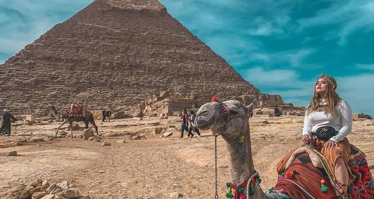 Person, die auf einem Kamel in der Nähe der Pyramide von Gizeh reitet.