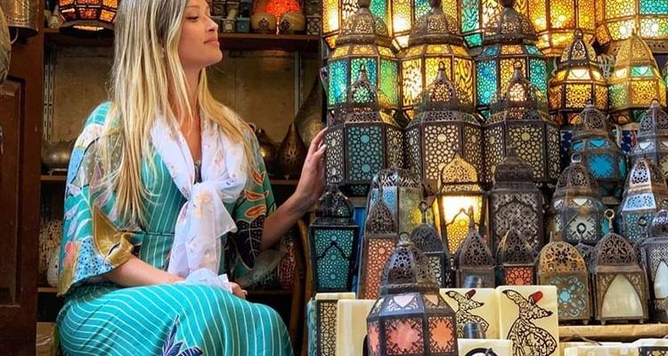 Frau, die zwischen traditionellen Laternen auf einem Markt sitzt.