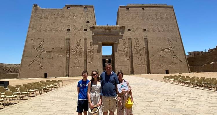 Familie posiert mit einem Touristenschild vor einem Tempel.