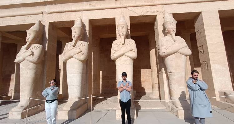 Touristen, die Statuen in einem antiken Tempel nachahmen.