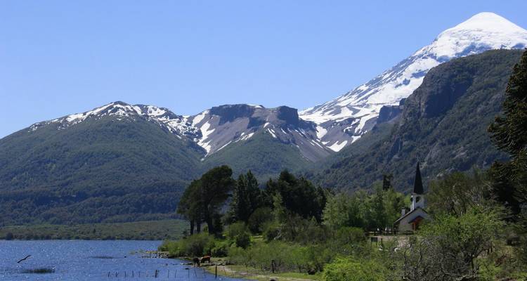 Een schilderachtig landschap met een met sneeuw bedekte berg, een kerk en een meer.