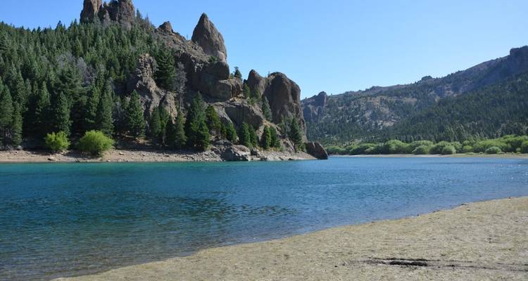 Een rotsachtige kustlijn bij een kalm, helder wateroppervlak.
