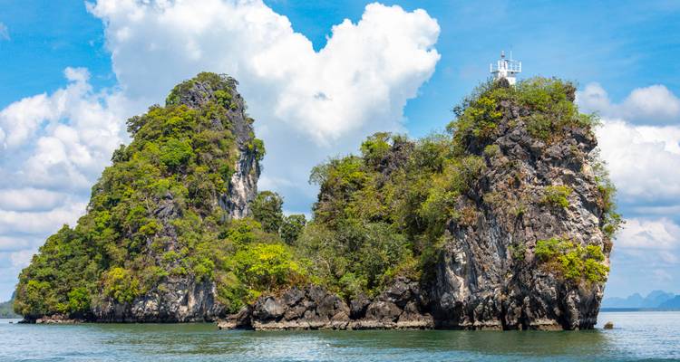 Twin jungle-covered limestone islets rise from turquoise Andaman Sea under puffy white clouds.