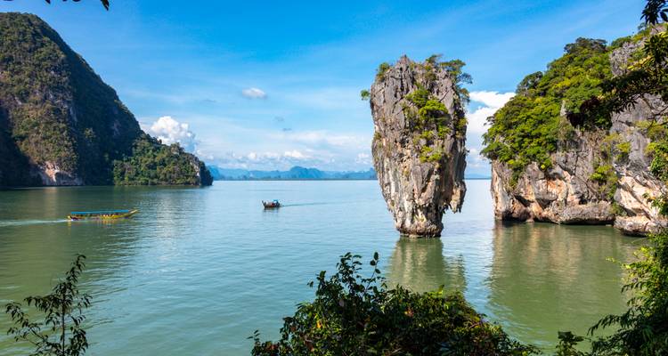 Iconic vertical limestone karst of James Bond Island set within calm green bay and surrounding cliffs.