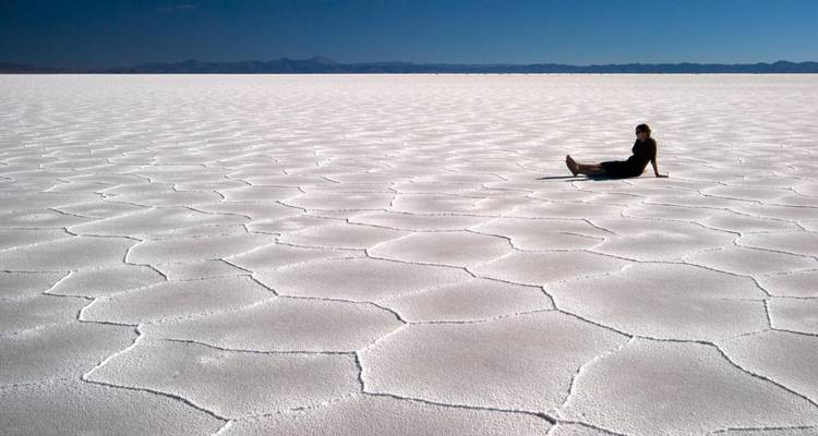 Vastes étendues de sel blanc avec une personne assise sur le sol.