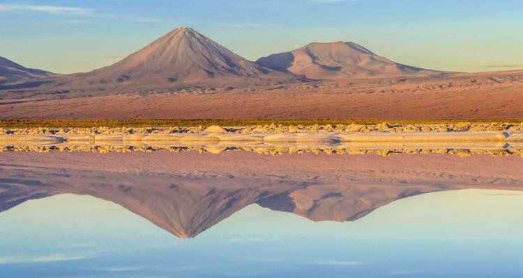 Un paisaje desértico sereno con un lago que refleja las montañas.
