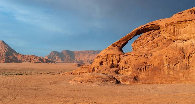 Formation d'arche de roche rouge dans un paysage désertique.
