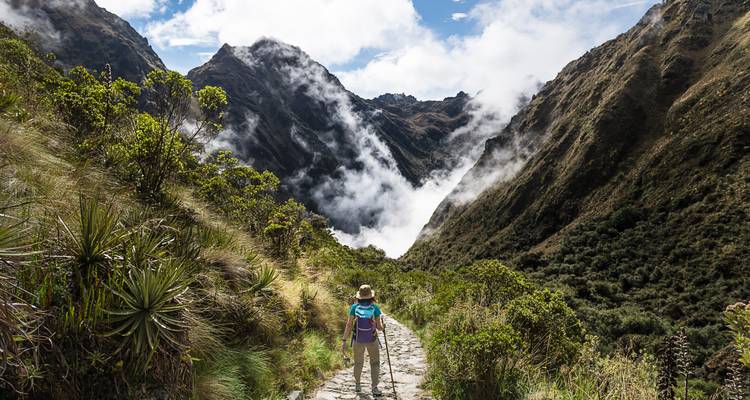 Person hiking down a path into a cloud-filled valley.