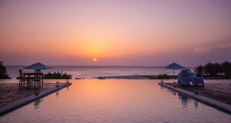 Infinity pool at sunset with a view of the ocean.