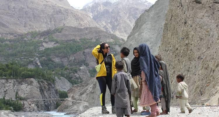 Gruppe von Menschen, die auf einer felsigen Landschaft mit Bergen im Hintergrund stehen.
