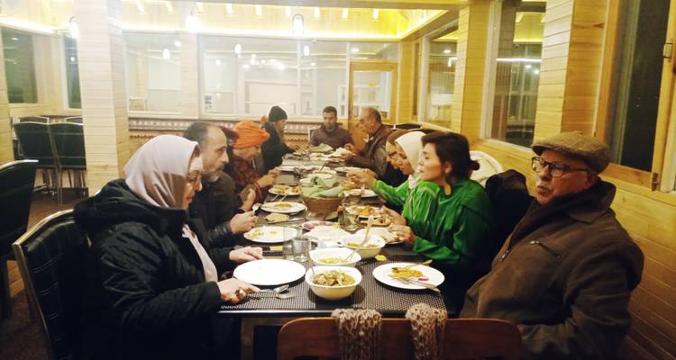 Gruppe von Menschen, die gemeinsam drinnen speisen.