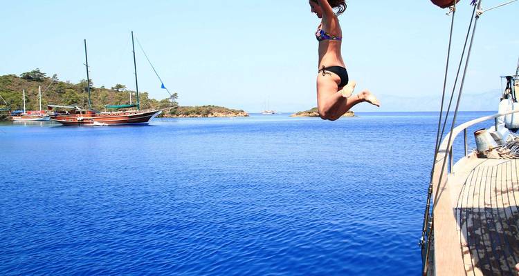 Personne sautant dans la mer bleue depuis un bateau.