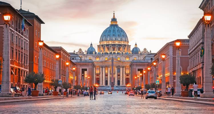 Sint-Pietersbasiliek in Vaticaanstad bij zonsondergang met mensen op straat.