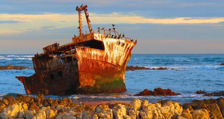 Épave rouillée sur un rivage rocheux.