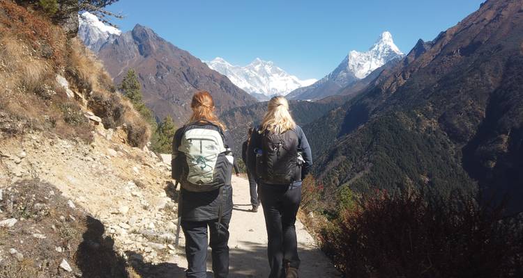 Deux personnes faisant de la randonnée sur un sentier de montagne avec de magnifiques sommets au loin.