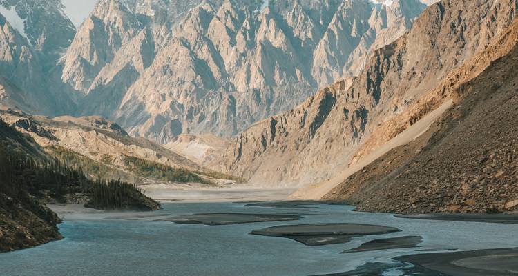 Goudgeel licht verlicht steile bergwanden terwijl een mistige rivier zich door de afgelegen dalbodems kronkelt.