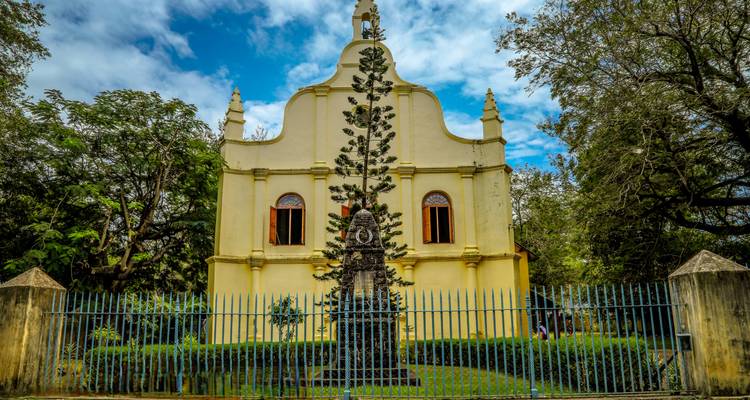Une église historique avec un jardin bien entretenu et une arche ornementale.