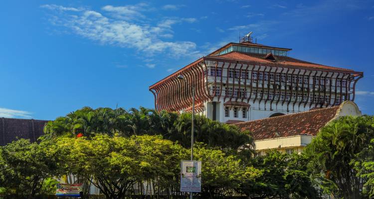 Un grand bâtiment moderne avec une architecture distincte entouré d'arbres.