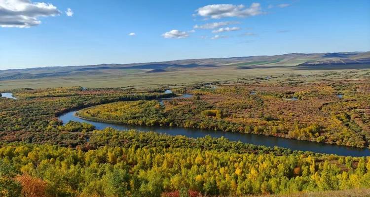 Weitläufige Landschaft mit einem sich windenden Fluss und lebendiger Vegetation.