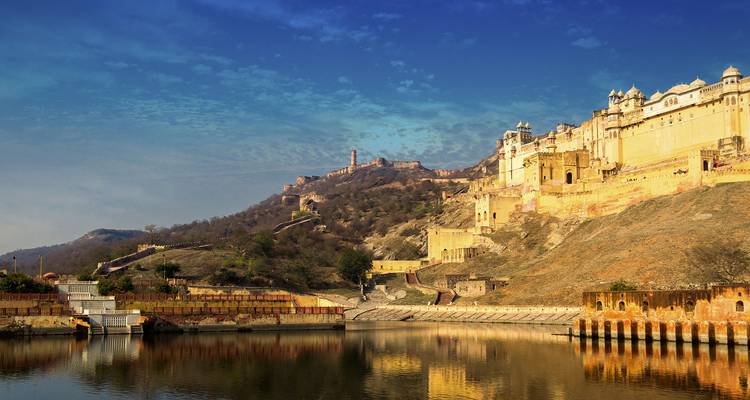 Mauern und Wälle des Amber Fort spiegeln sich in einem ruhigen See unter blauem Himmel