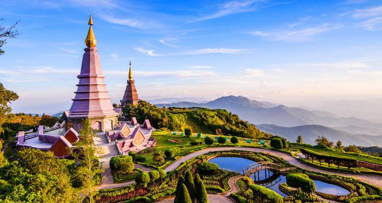 Zwei prächtige Stupas vor einer Bergkulisse.