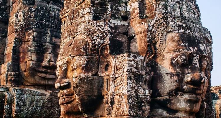 Close-up view of the iconic carved stone faces of Bayon Temple in Angkor Thom, showing detailed sandstone textures and lichen patterns.