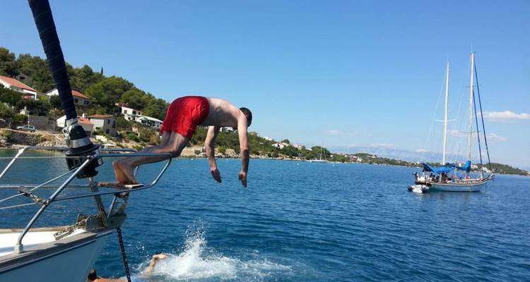 Persoon die vanaf een boot de zee induikt.