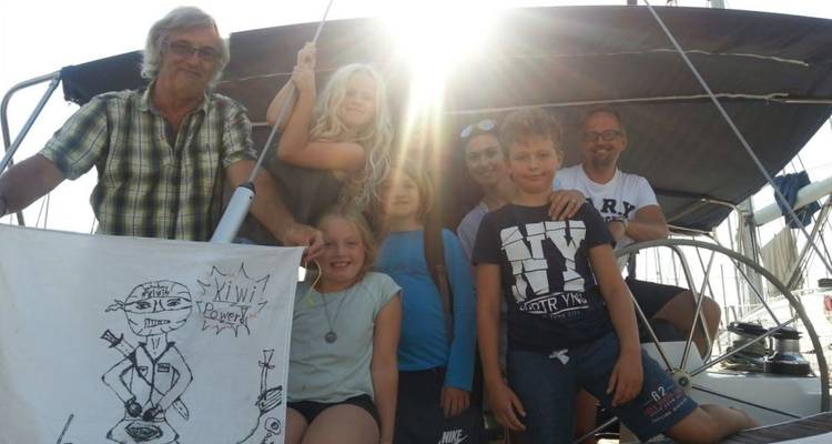 Familie poseert op een zeilboot met zonlicht achter hen.