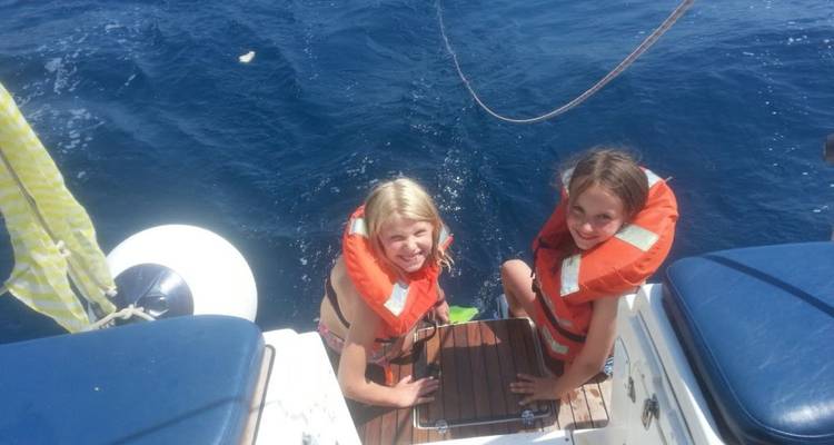Twee kinderen in reddingsvesten die achterin een boot zitten.
