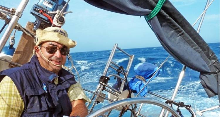 Un hombre dirigiendo un velero a través de olas marinas agitadas.