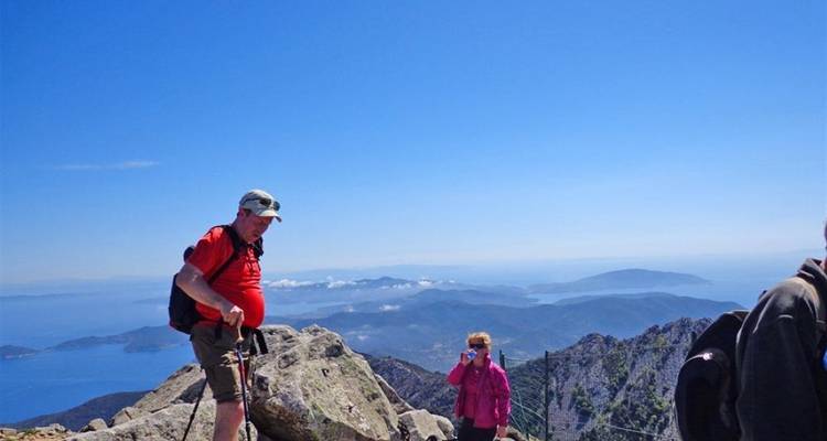 Excursionistas en una cima rocosa con vistas panorámicas del mar.