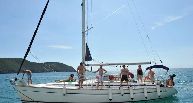 Eine Gruppe von Menschen, die auf einem Segelboot in offenen Gewässern stehen und sich entspannen.