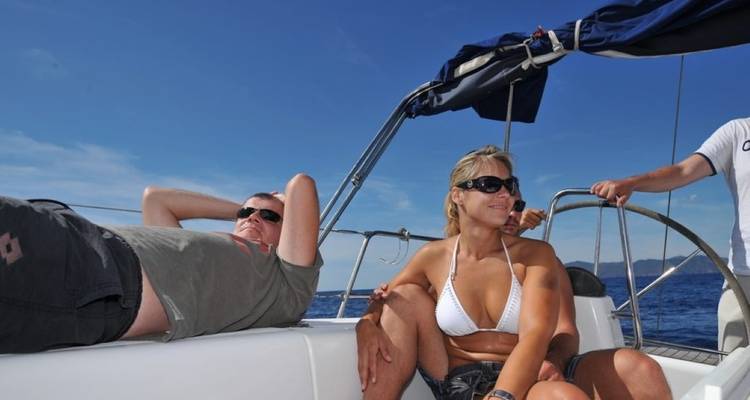 Zwei Menschen entspannen auf einem Segelboot in der Sonne.