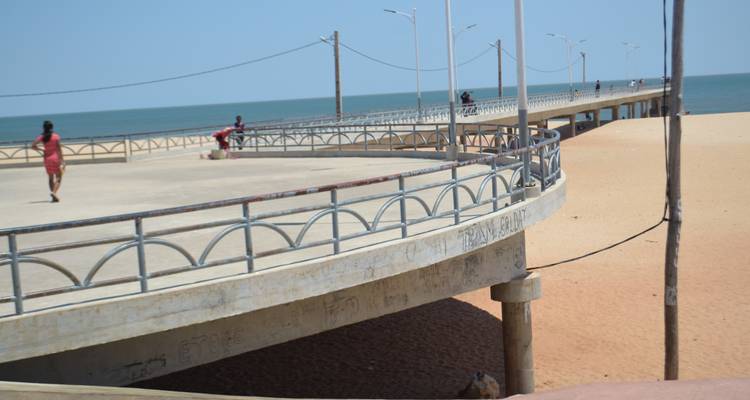 Man loopt op de promenade bij de oceaan.