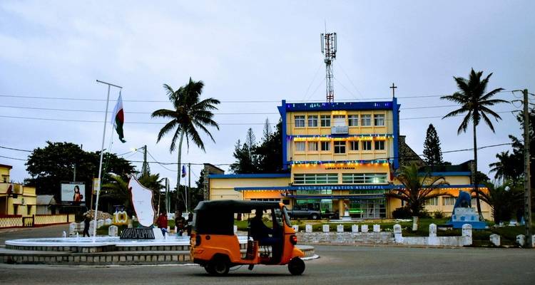 Kleurrijke tuk-tuk voor een gemeentelijk gebouw met vlaggen en lichten.