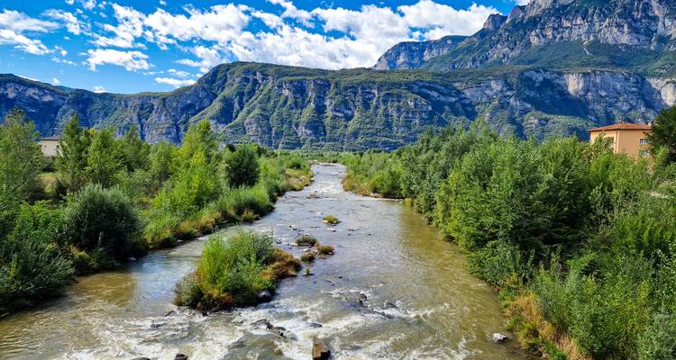 Snelstromende rivier die door een weelderig dal snijdt onder hoge rotswanden.