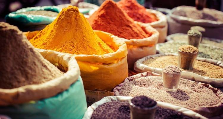 Verschiedene bunte Gewürze in Säcken, die auf einem Markt ausgestellt sind.