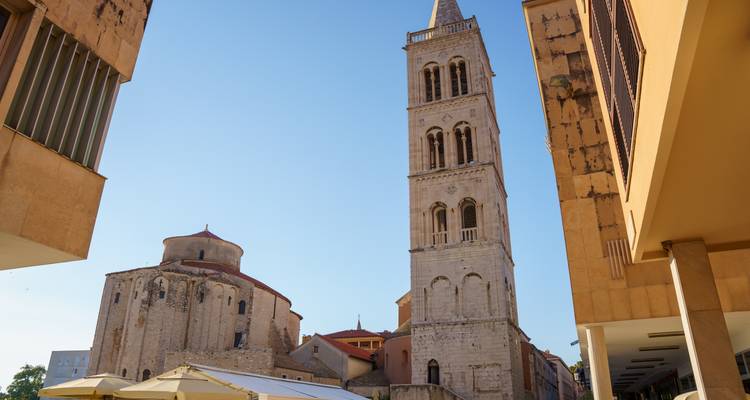 Haute tour romane circulaire et église circulaire de Saint-Donat encadrées par des bâtiments modernes à Zadar.